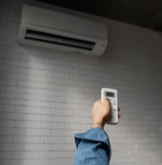 person using remote control on air conditioning